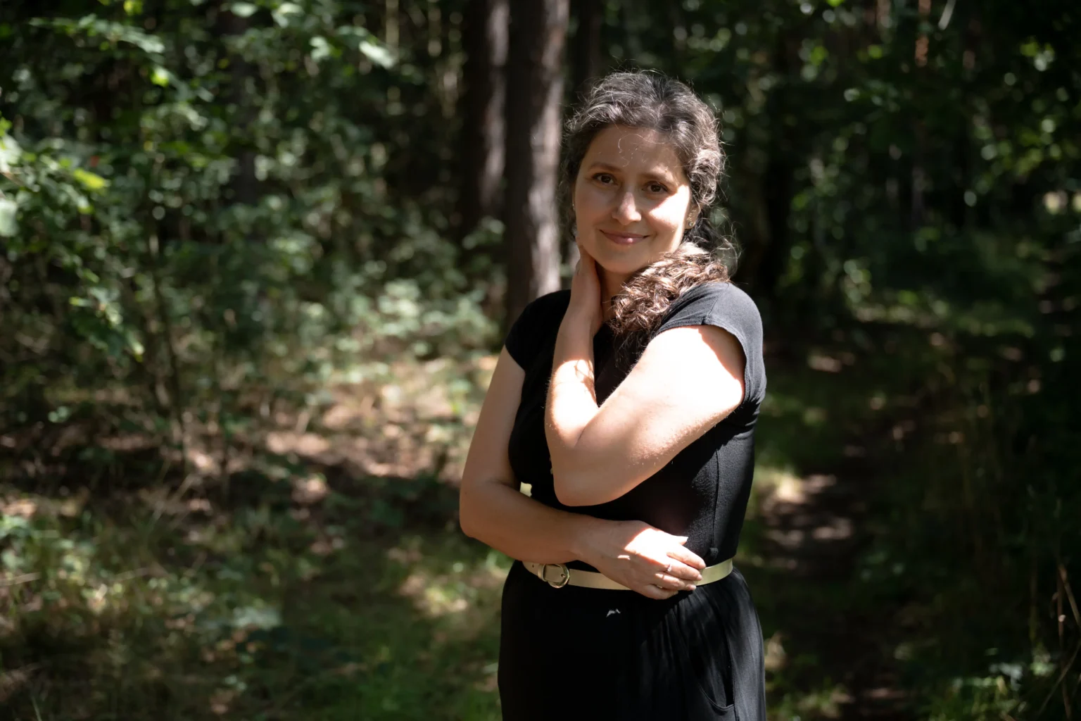 Bára stojí v&nbsp;lese s&nbsp;jemným úsměvem kouká do&nbsp;objektivu