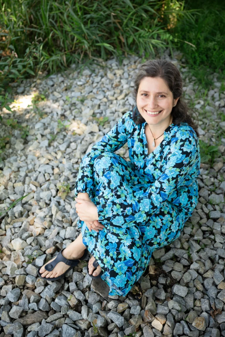 Bára v květovaných šatech se usmívá a sedí na kamínkách